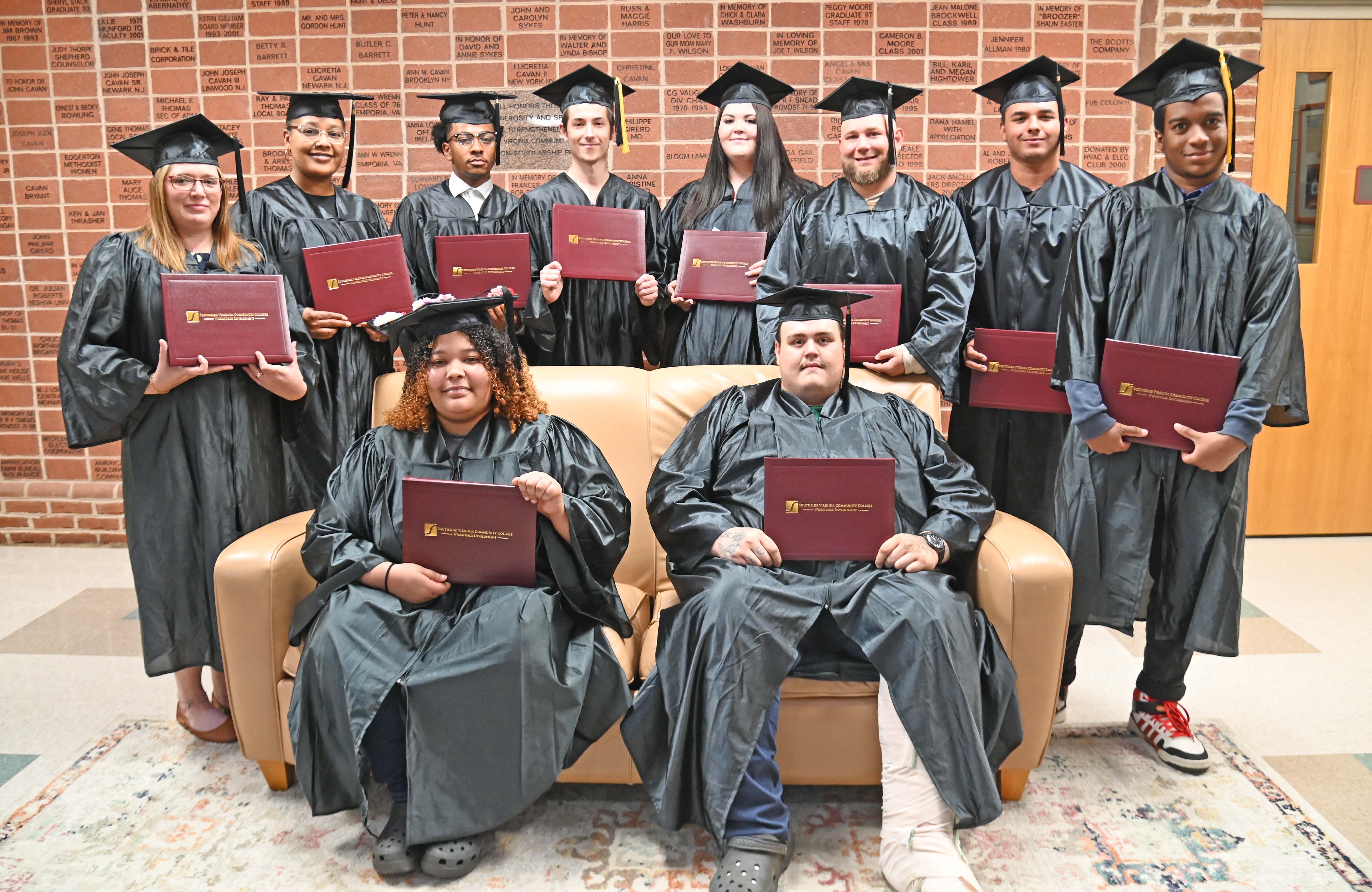 Group of students in graduation regalia posed with certificates