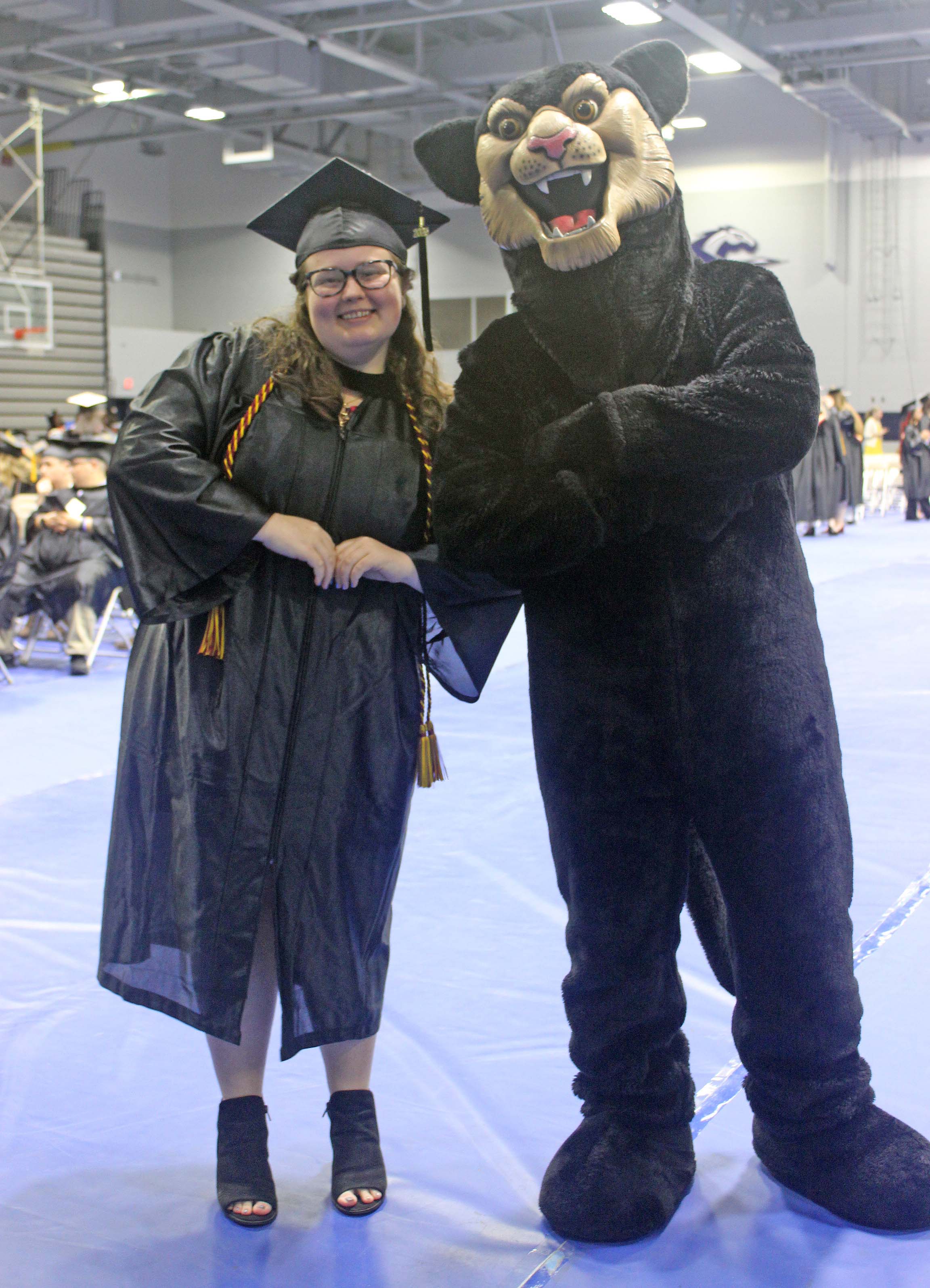Elizabeth Farrell poses with Johnny Paws mascot in Longwood gym at SVCC graduation 2025