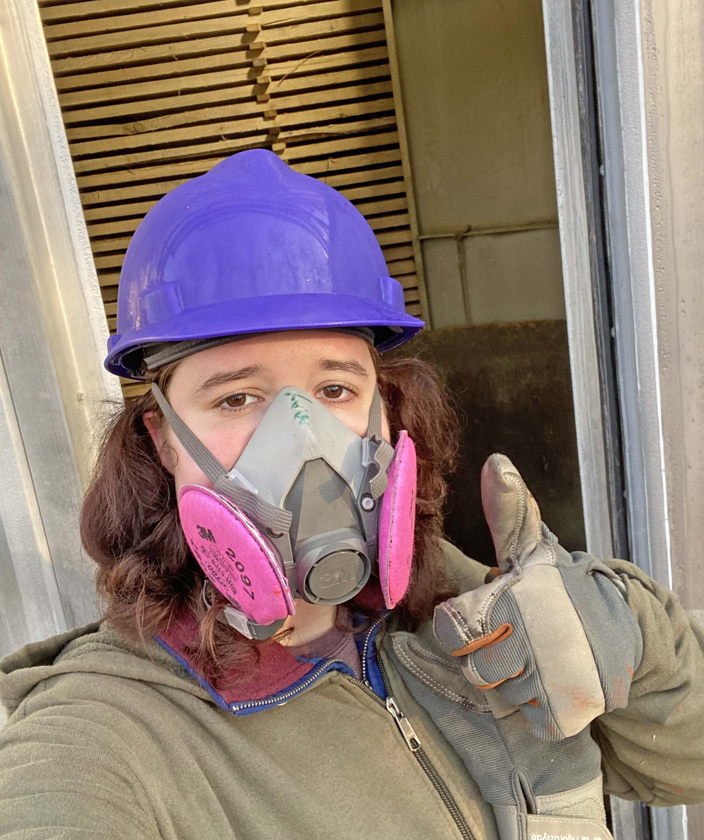 SVCC Student May Levonian in a purple hardhat and mask giving a thumbs up