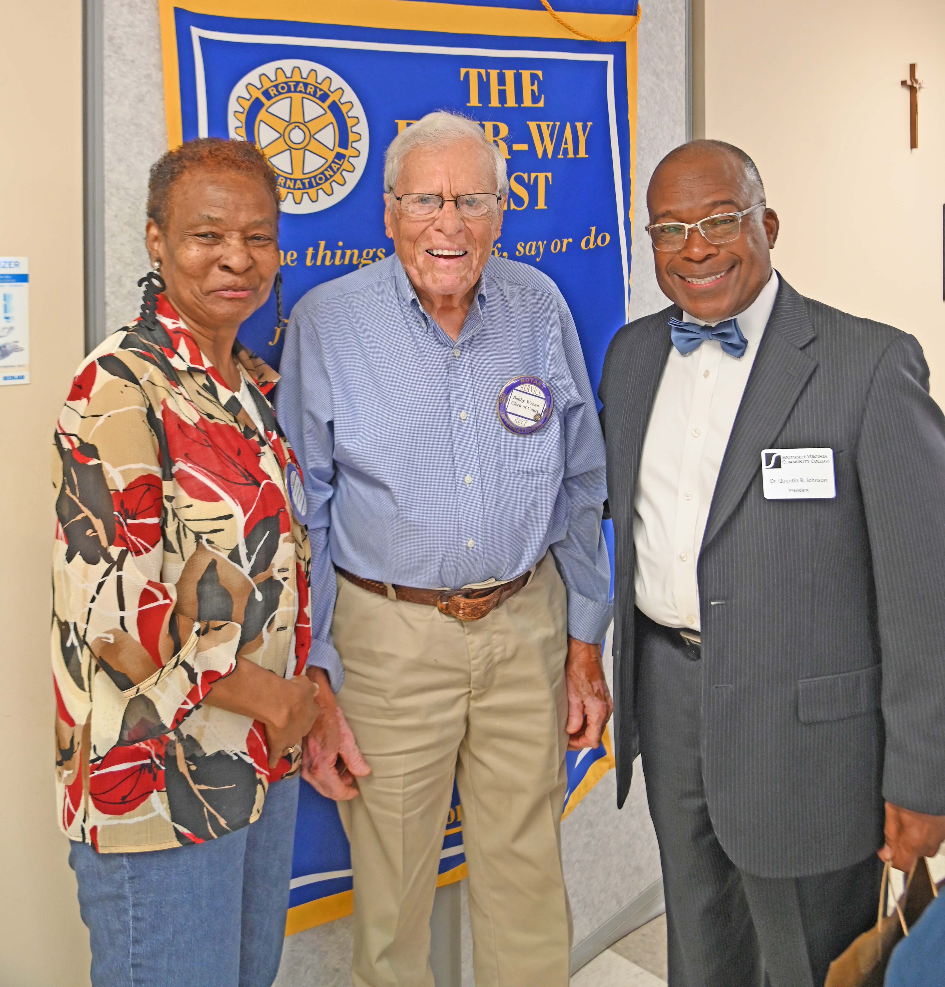 Marva Dunn, Bobby Wrenn, and Dr. Quentin Johnson standing in front of the Rotary banner