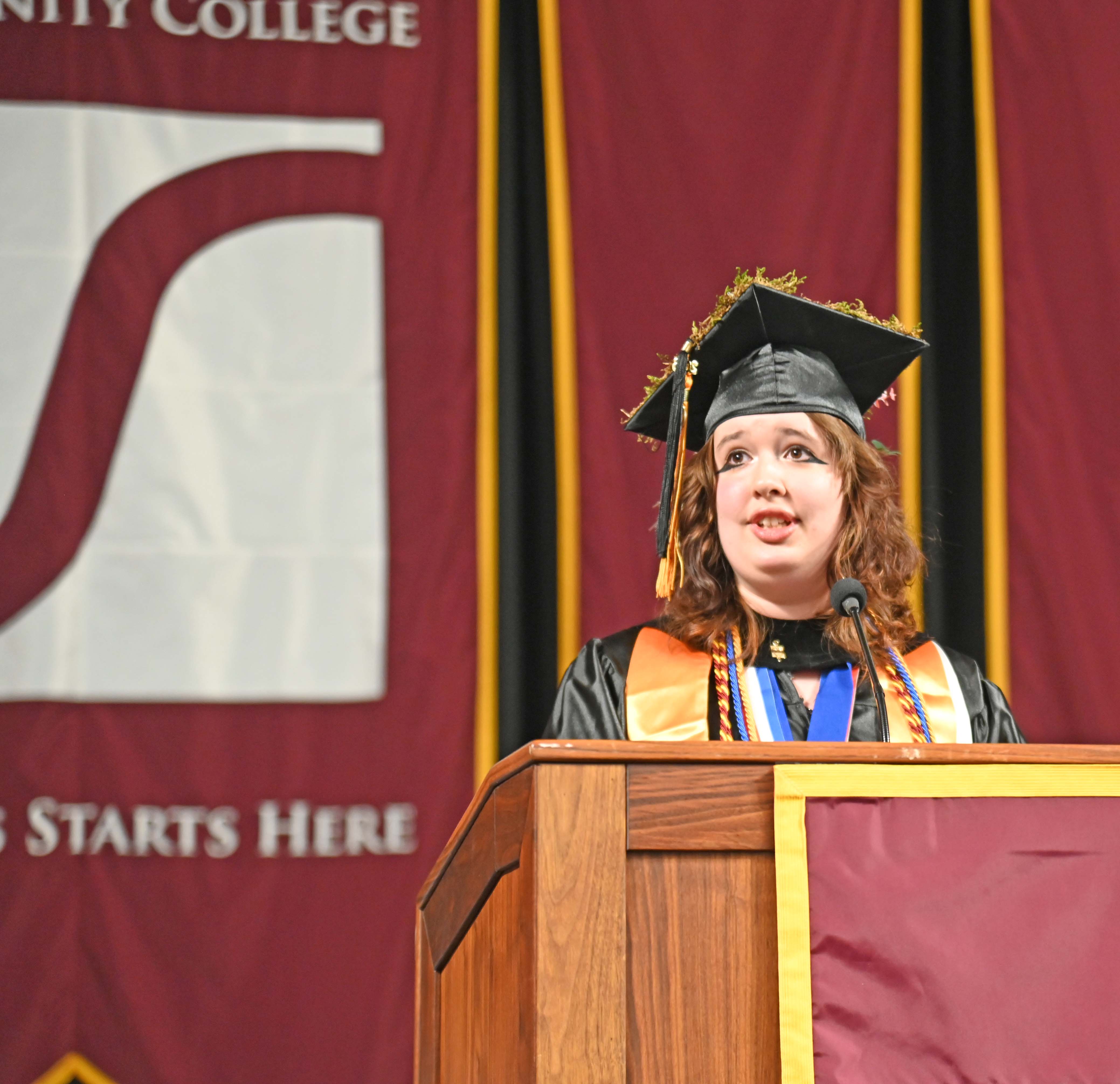 SVCC student May Levonian in graduation regalia speaking at a podium in front of the SVCC banner
